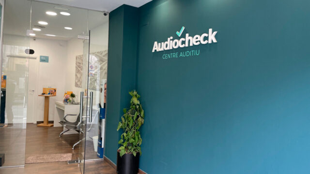 Entrada amb una paret pintada de color blau, on es veu el logotip Audiocheck, Centre Auditiu.
