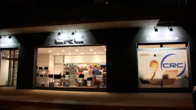 Fotografia feta durant la nit des de l'exterior, de l'aparador Informàtica CRC.