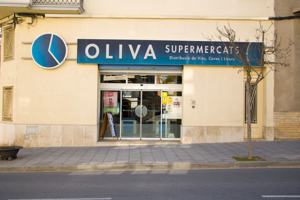 Fotografia des de l'exterior, de l'entrada al supermercat Oliva.