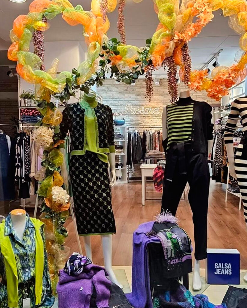 Fotografia de l'aparador Passarel·la on es poden veure diferents looks de primavera per dona, colors com el verd, el taronja, el blanc o el negre són alguns dels colors que es poden veure a l'aparador.